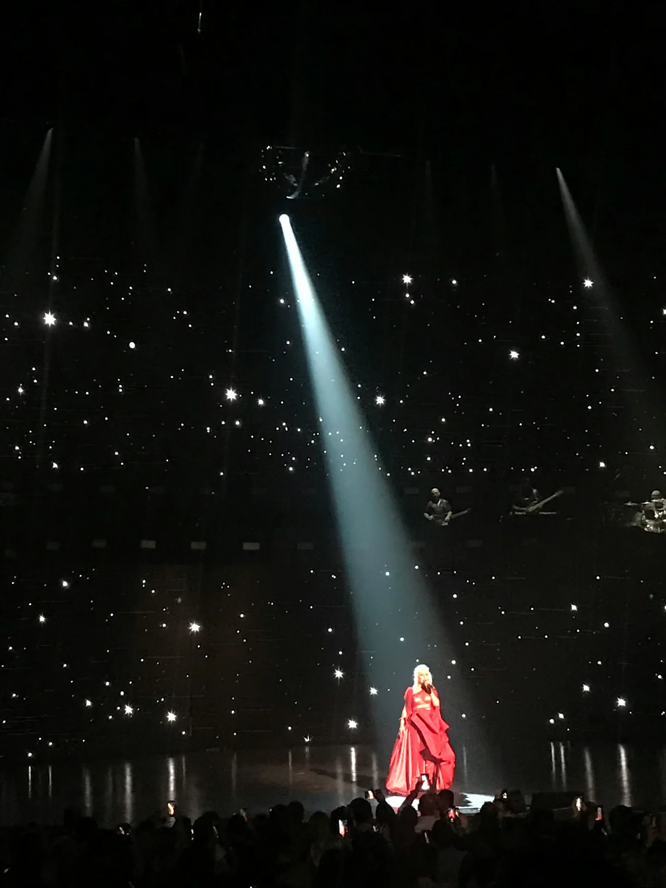 A performer in red beneath a theatrical spotlight